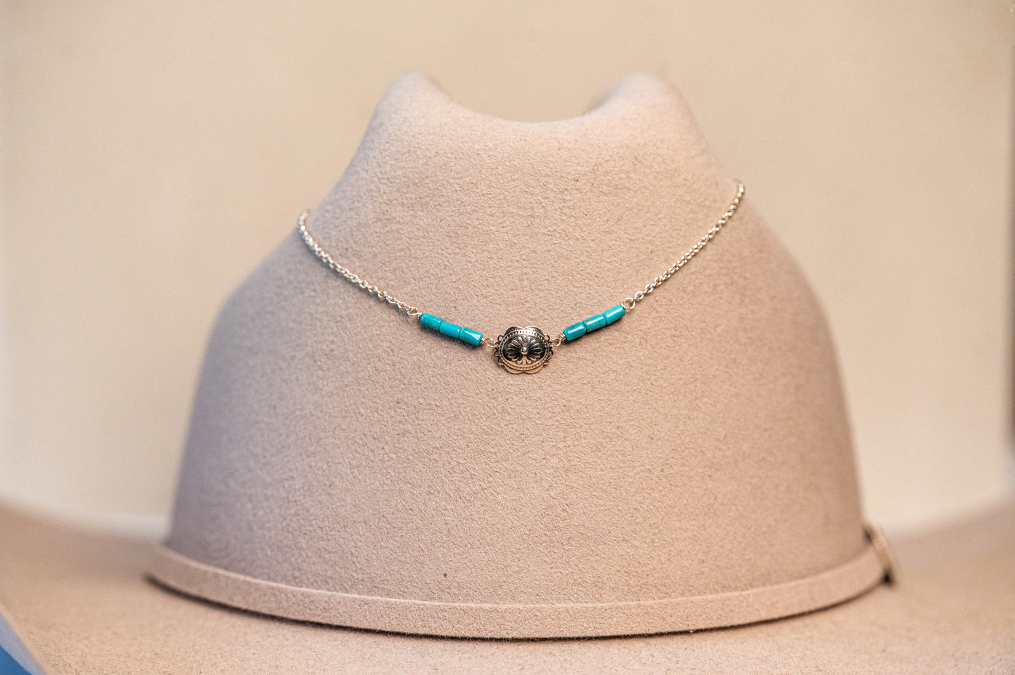 Necklace with Turquoise beads on a beige STETSON bust against a beige background