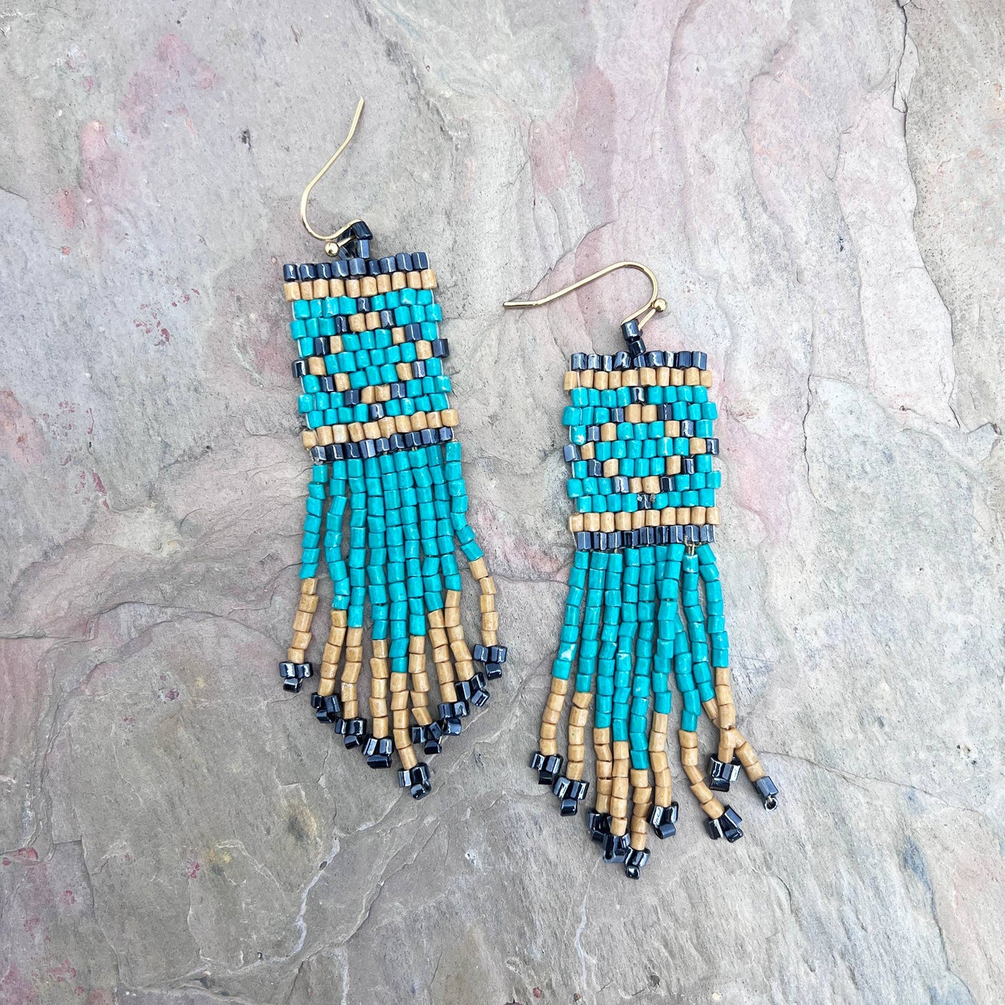 Pair of beaded earrings on a textured stone surface