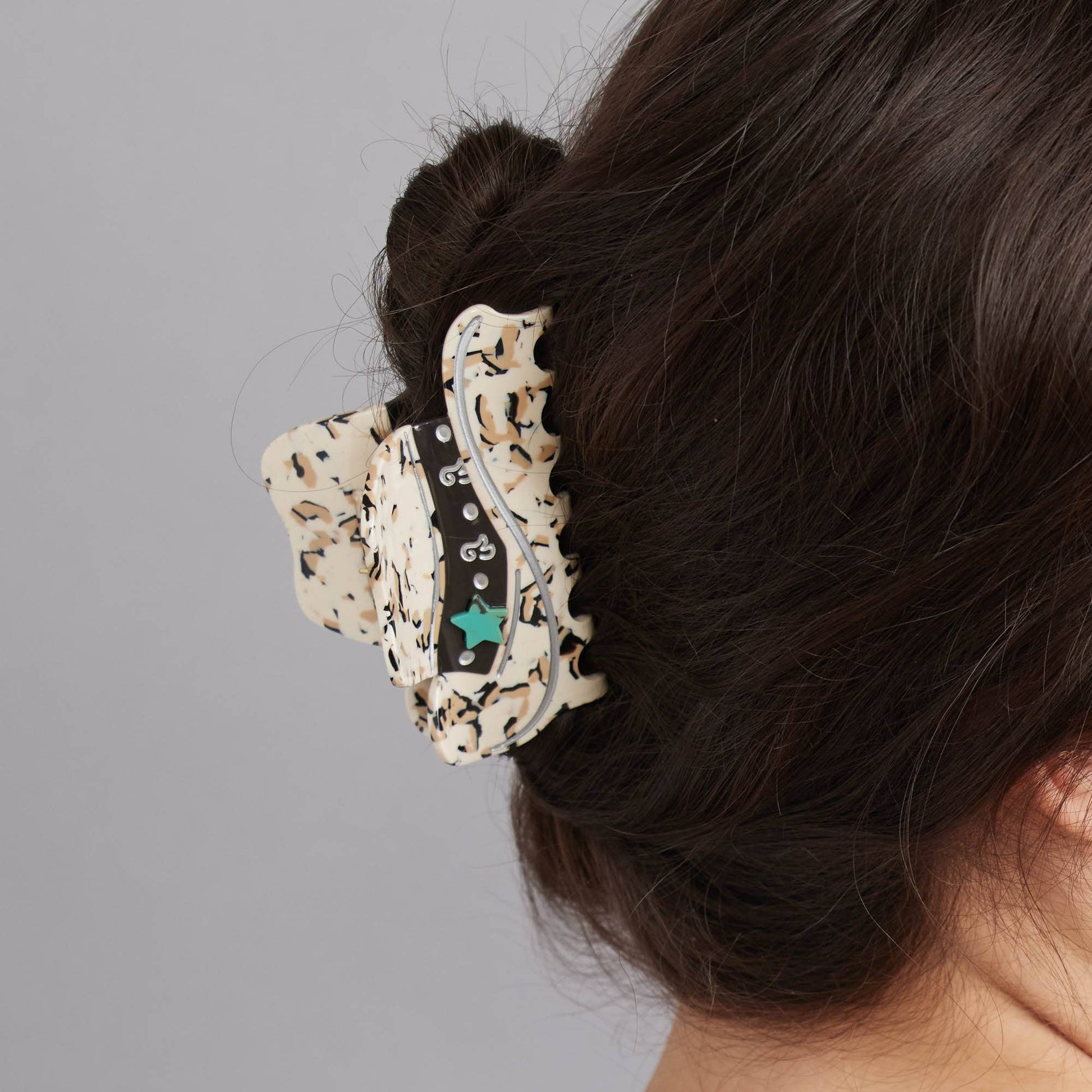 Decorative hair clip on a bun against a gray background