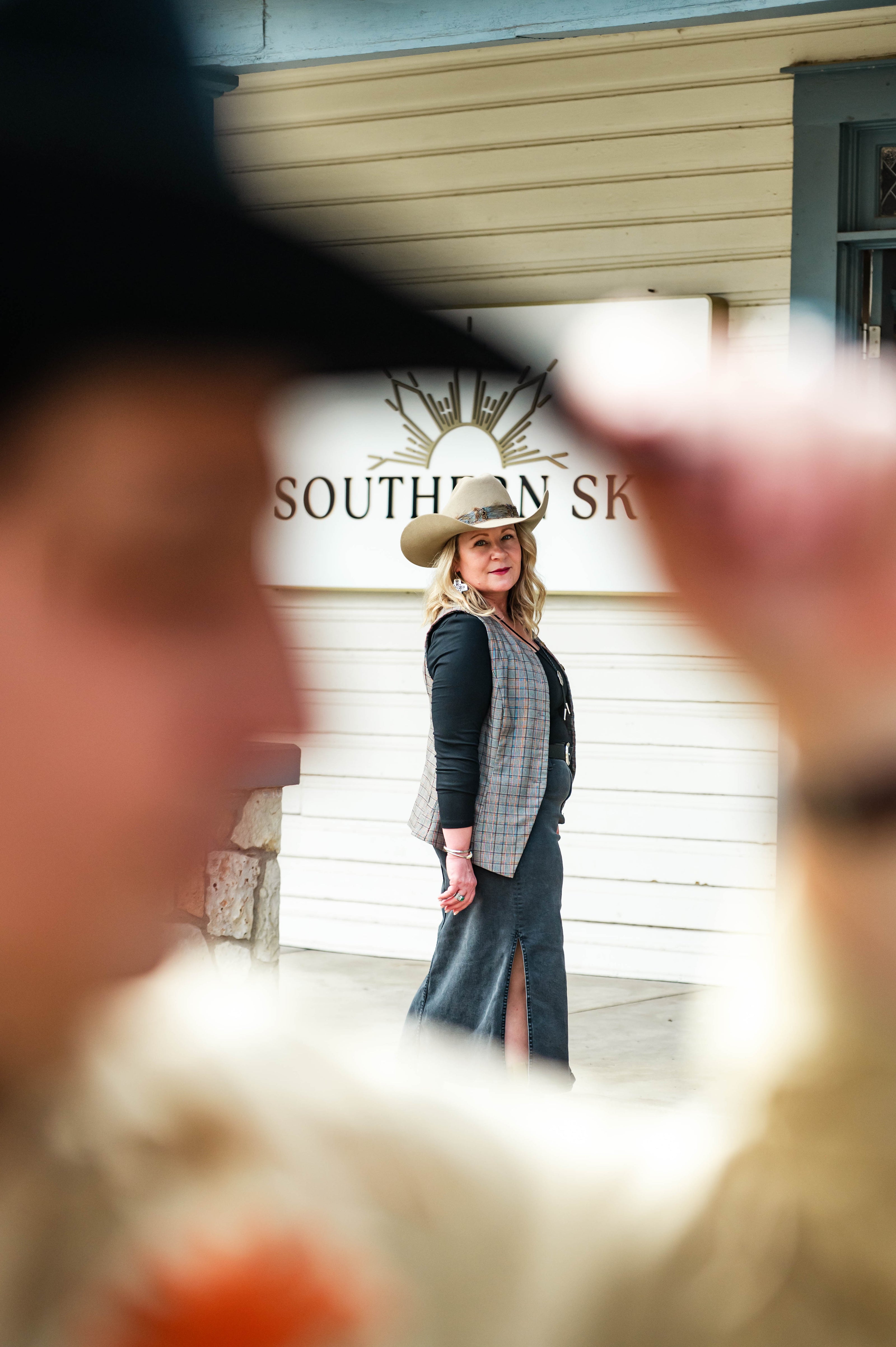 Woman wearing a STETSON cowboy hat in front of a building with 'Southern Sky' sign.