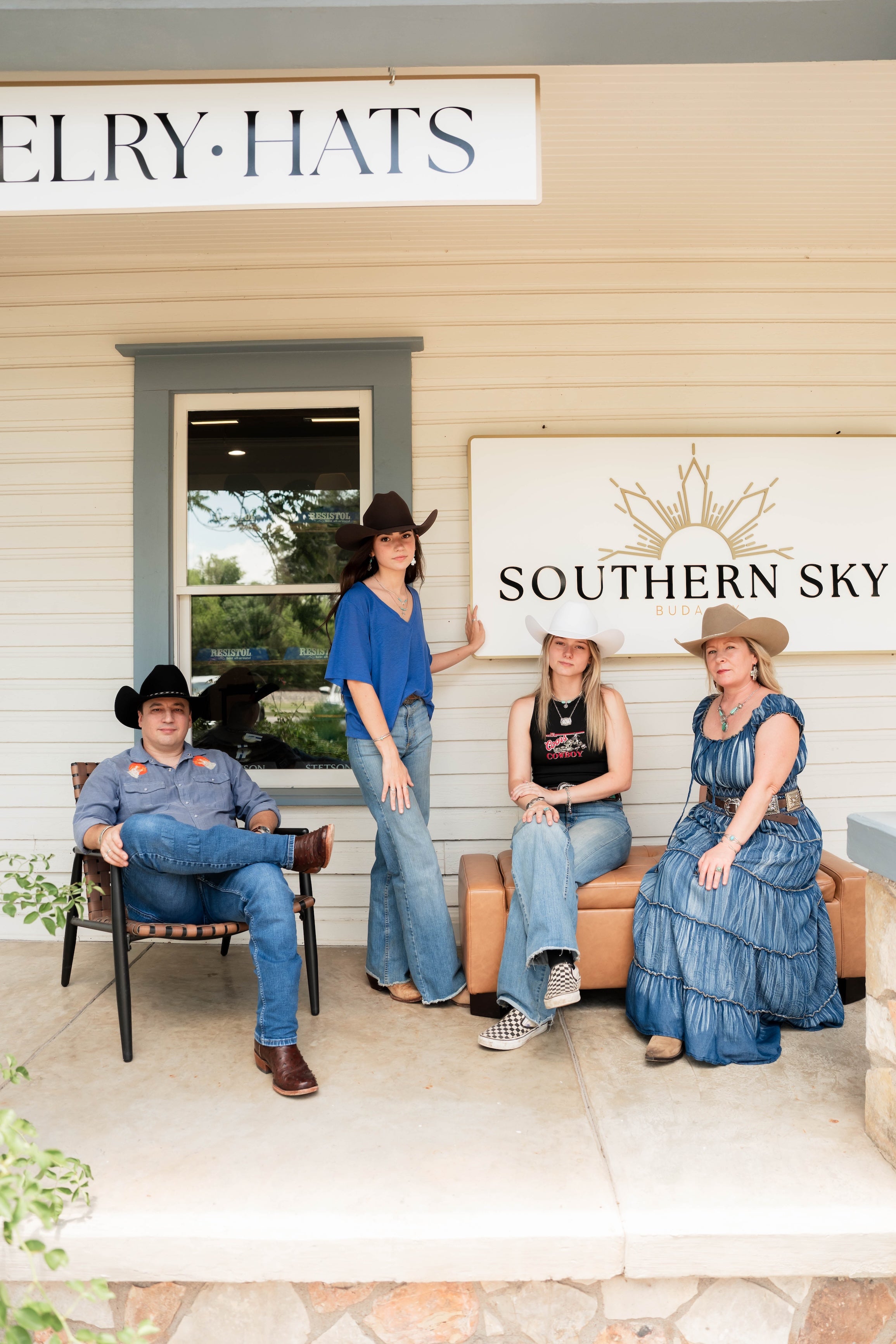 Four people wearing cowboy hats in front of a store with 'Southern Sky' branding.